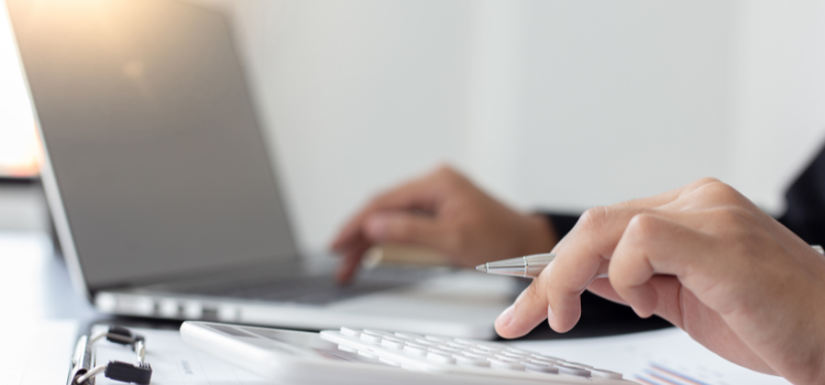 ノートパソコンと計算機とで相続の費用を計算している。